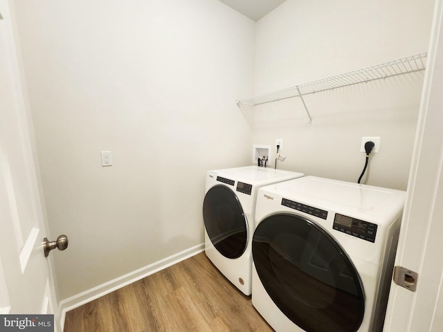 clothes washing area featuring laundry area, baseboards, light wood-style floors, and separate washer and dryer