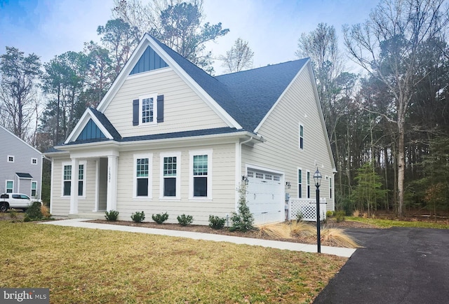 view of front of house with roof with shingles, an attached garage, a front lawn, aphalt driveway, and board and batten siding