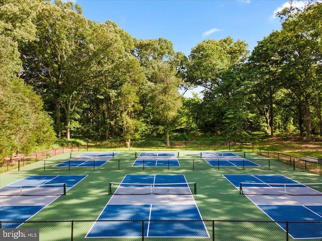 view of tennis court with community basketball court and fence