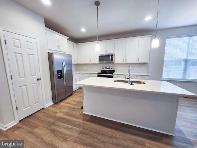 kitchen with a sink, tasteful backsplash, wood finished floors, stainless steel appliances, and light countertops