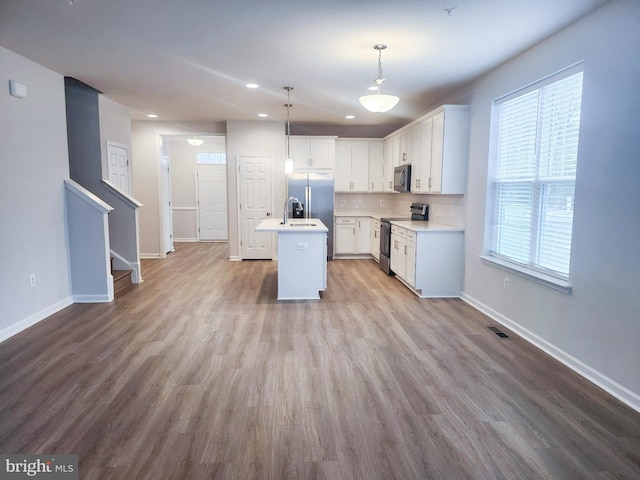 kitchen featuring wood finished floors, visible vents, decorative backsplash, light countertops, and appliances with stainless steel finishes