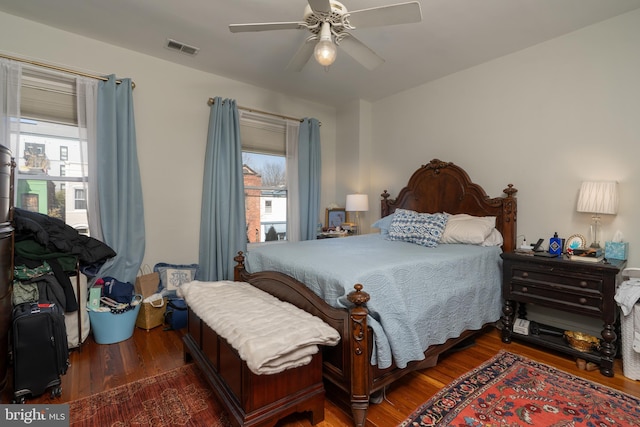 bedroom with visible vents, multiple windows, wood finished floors, and a ceiling fan