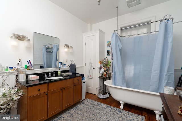 full bath with a shower with curtain, a freestanding bath, wood finished floors, and vanity