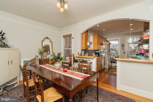 dining room featuring arched walkways, recessed lighting, and dark wood-style flooring