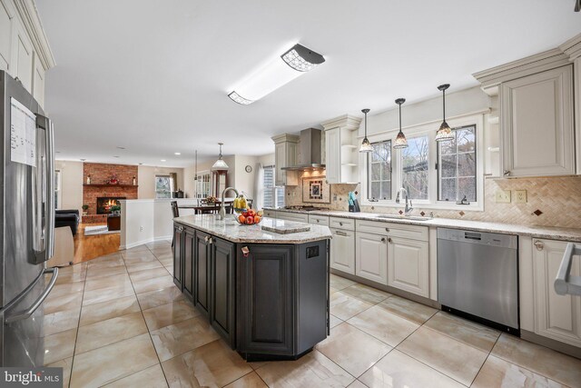 kitchen featuring plenty of natural light, wall chimney exhaust hood, stainless steel appliances, and a sink