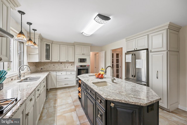 kitchen with cream cabinetry, stainless steel appliances, a center island with sink, and a sink