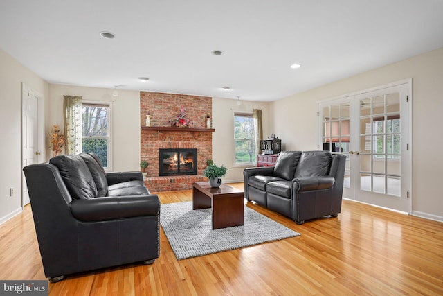 living room featuring french doors, light wood-style flooring, baseboards, a brick fireplace, and recessed lighting