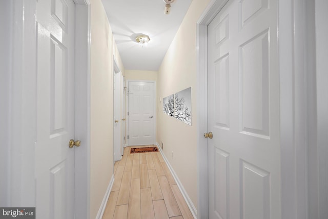 hall featuring baseboards and wood finish floors