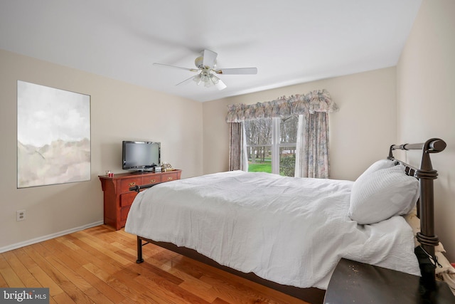 bedroom with light wood finished floors, baseboards, and a ceiling fan