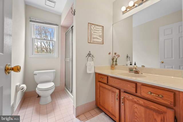 bathroom with a shower stall, toilet, tile patterned floors, and baseboards