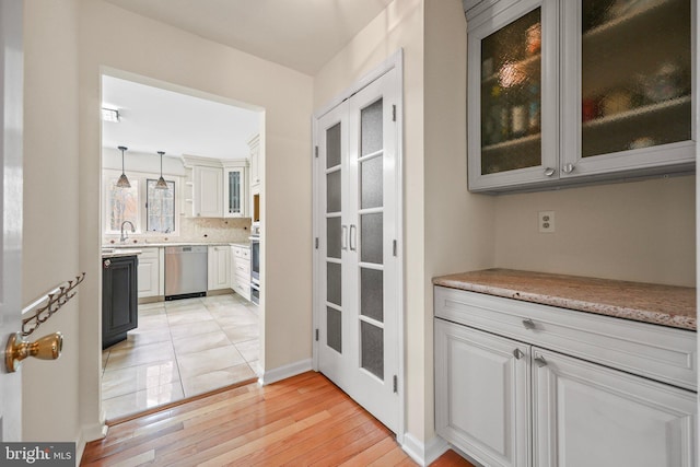 interior space featuring light wood finished floors, stainless steel appliances, decorative light fixtures, baseboards, and tasteful backsplash