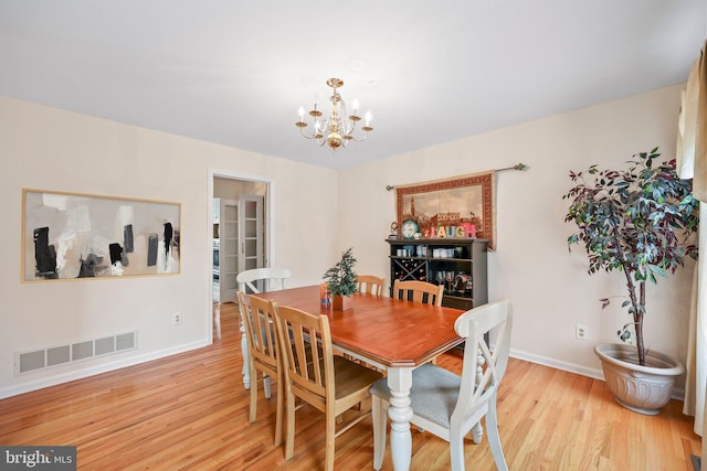 dining space with baseboards, wood finished floors, visible vents, and a notable chandelier
