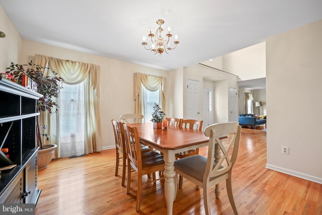 dining space with light wood-style flooring, baseboards, and a chandelier