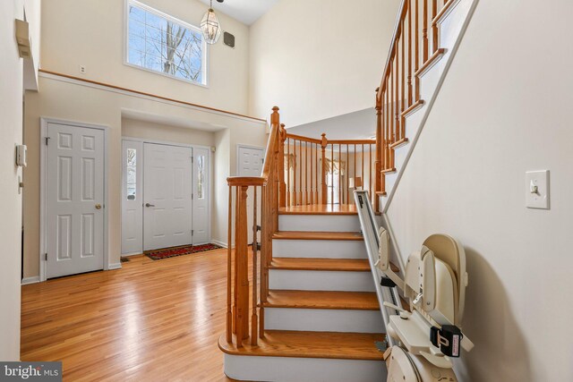 foyer featuring baseboards, wood finished floors, a high ceiling, and stairs