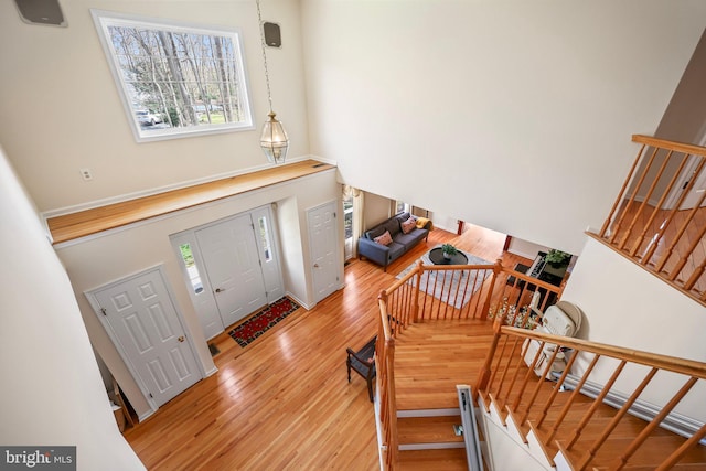 entrance foyer with a high ceiling, stairs, and light wood finished floors