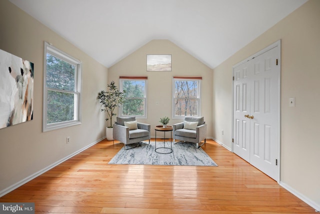 living area with lofted ceiling, light wood finished floors, and baseboards