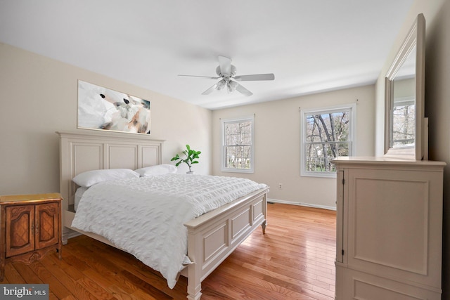 bedroom featuring a ceiling fan, baseboards, and light wood-style floors