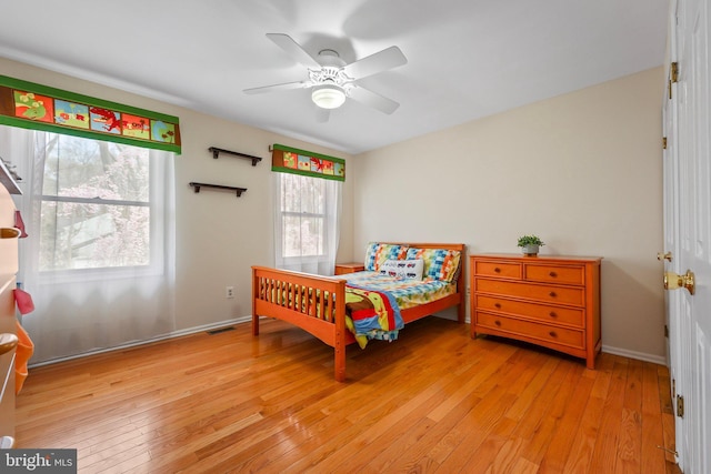 bedroom with baseboards, a ceiling fan, visible vents, and light wood-type flooring