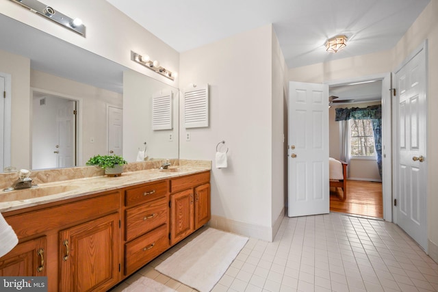 bathroom with tile patterned floors, a sink, ensuite bathroom, double vanity, and baseboards