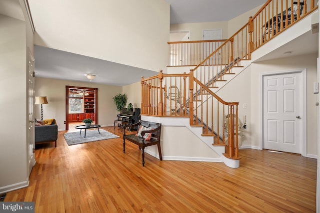 interior space with wood-type flooring, a high ceiling, and baseboards