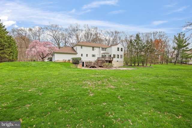 back of property with a wooden deck and a yard