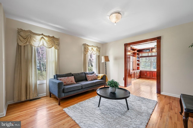 living area featuring light wood-style flooring, visible vents, and baseboards
