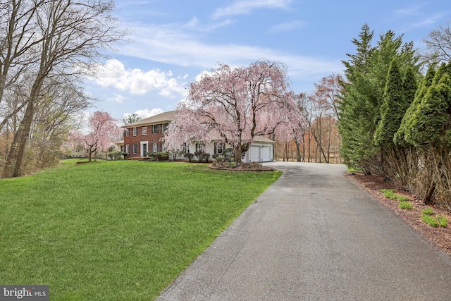 view of front of property with a front lawn, an attached garage, and aphalt driveway