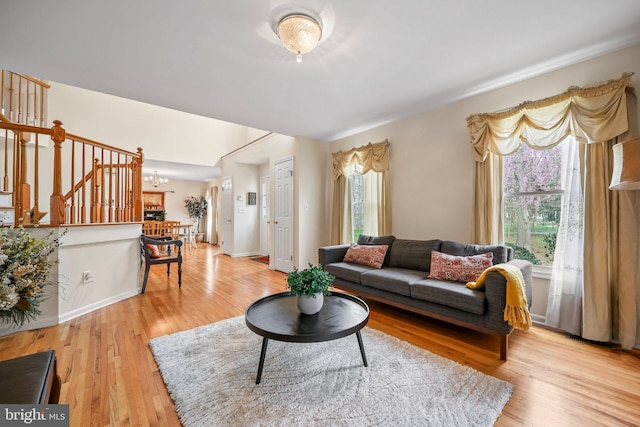 living area featuring stairway, a chandelier, and light wood finished floors