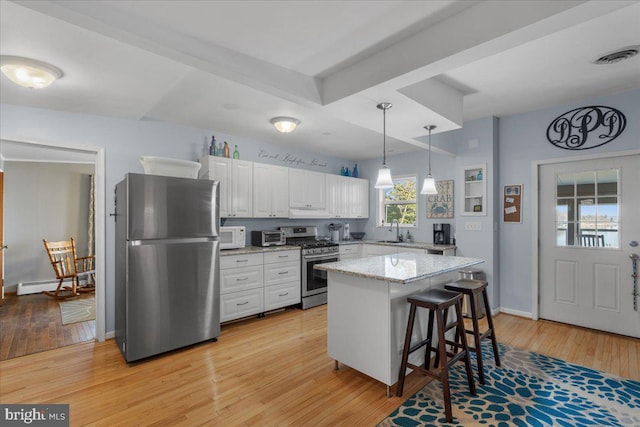 kitchen featuring white cabinets, appliances with stainless steel finishes, light wood-type flooring, and a sink