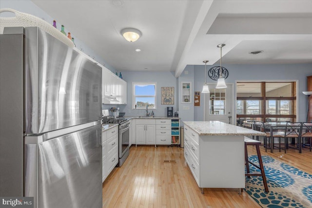 kitchen with light stone countertops, visible vents, light wood finished floors, appliances with stainless steel finishes, and white cabinetry