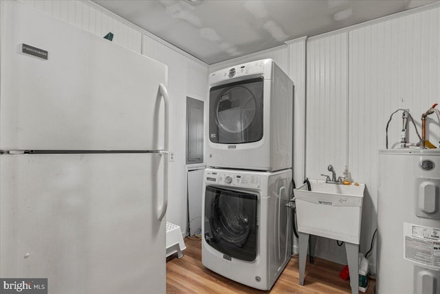 laundry area featuring water heater, stacked washer / dryer, laundry area, and light wood-type flooring