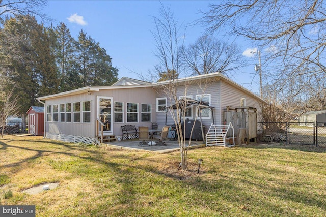 back of property featuring an outbuilding, a lawn, fence, a storage shed, and a patio area