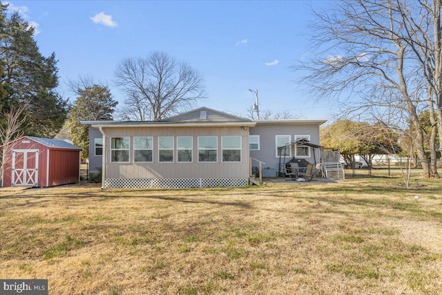 rear view of property with a lawn, a storage unit, an outdoor structure, and fence