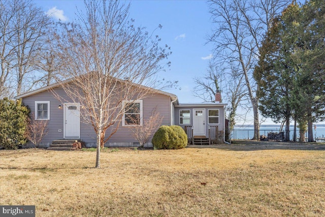 view of front of house featuring a water view, a chimney, a front lawn, and entry steps