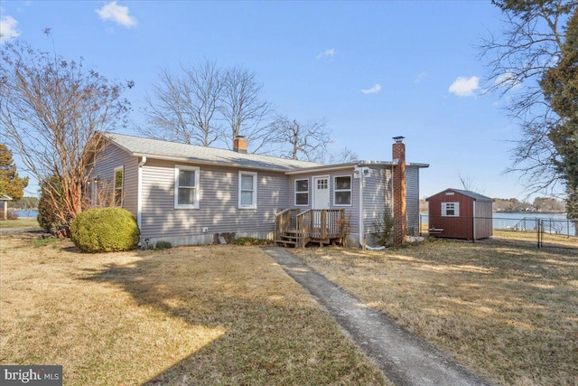 rear view of house featuring an outbuilding, fence, and a lawn