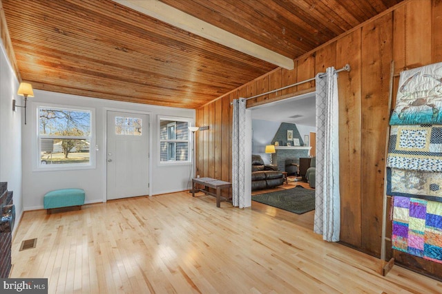 entrance foyer with visible vents, a fireplace, hardwood / wood-style flooring, wood walls, and wooden ceiling