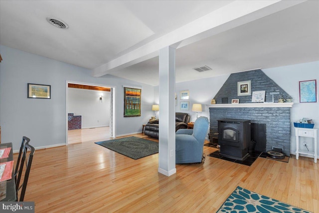 living room featuring visible vents, a wood stove, and wood finished floors