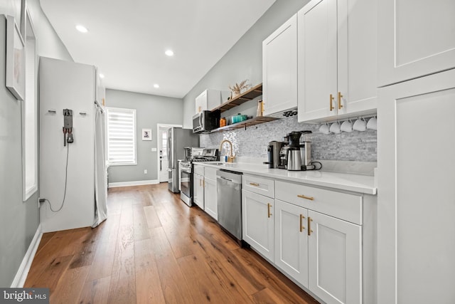 kitchen featuring hardwood / wood-style floors, light countertops, white cabinets, appliances with stainless steel finishes, and tasteful backsplash