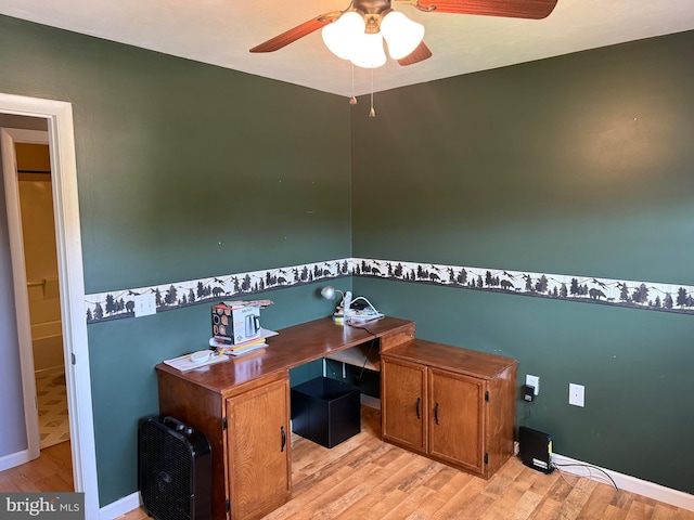 office space featuring baseboards, heating unit, light wood-style flooring, and ceiling fan