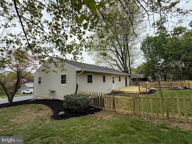 view of side of home with a fenced backyard, a wooden deck, and a yard