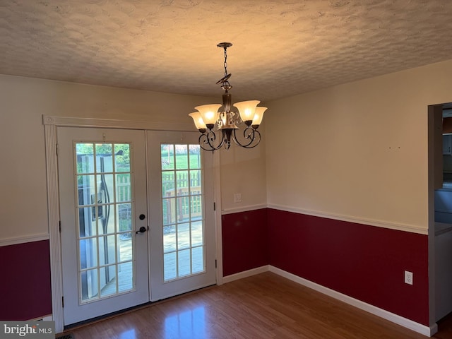 doorway to outside featuring wood finished floors, baseboards, a textured ceiling, french doors, and a notable chandelier