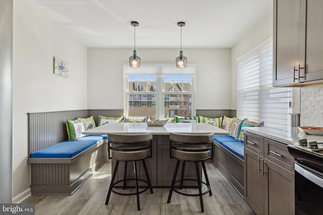 dining space featuring breakfast area, wainscoting, and light wood finished floors