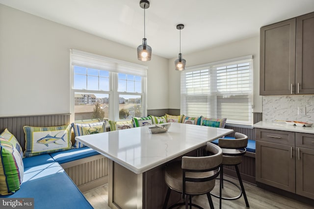 kitchen featuring a kitchen island, a wainscoted wall, breakfast area, a kitchen bar, and light wood-style flooring