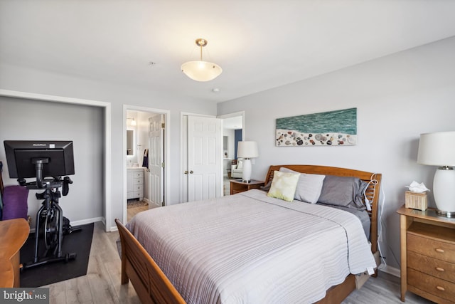 bedroom featuring ensuite bath, baseboards, and light wood finished floors