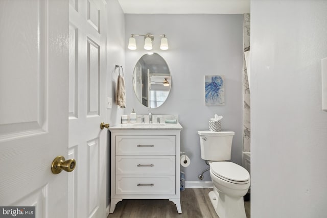 full bathroom with baseboards, toilet, shower / tub combo with curtain, wood finished floors, and vanity