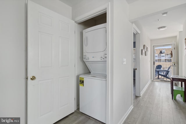 washroom with laundry area, baseboards, light wood-style floors, and stacked washer and dryer