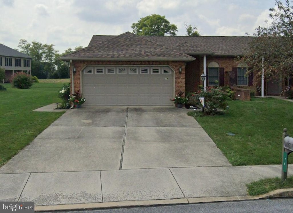 single story home with a garage, concrete driveway, a front yard, brick siding, and roof with shingles