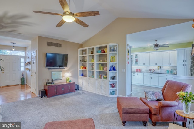 living room featuring light carpet, visible vents, a ceiling fan, and vaulted ceiling