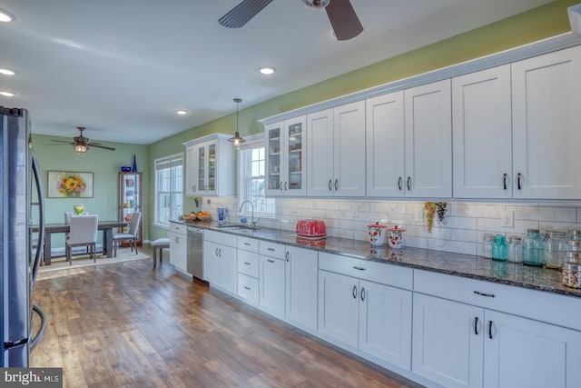 kitchen featuring tasteful backsplash, appliances with stainless steel finishes, wood finished floors, a ceiling fan, and a sink