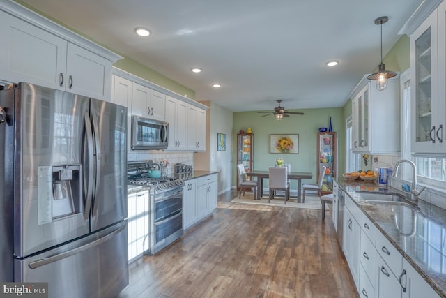 kitchen with dark stone countertops, white cabinets, appliances with stainless steel finishes, and a sink